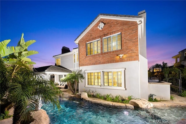 18345 Watson Way, Yorba Linda, CA 92886 - back of property at dusk featuring brick siding, a chimney, and an outdoor pool