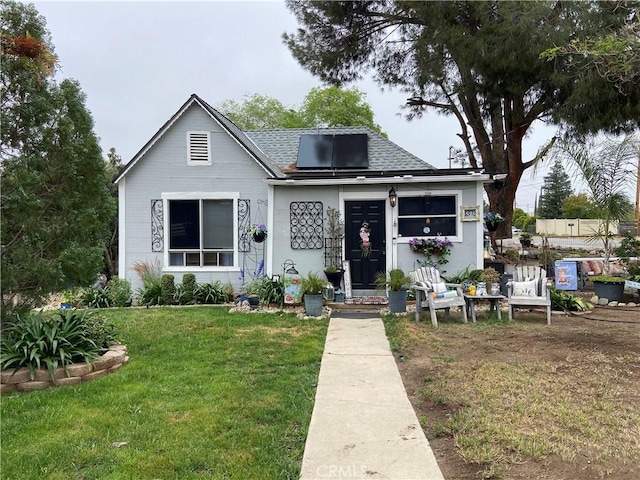 bungalow-style home with a shingled roof and a front lawn