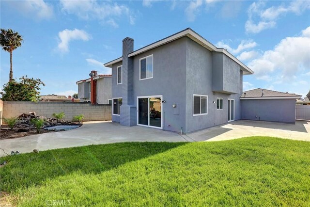 rear view of property featuring fence, a patio, and a yard