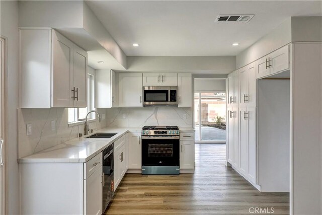 kitchen with white cabinets, stainless steel appliances, visible vents, and a sink