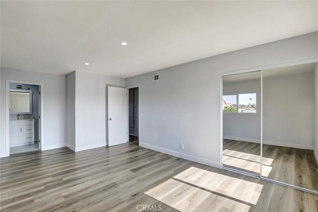unfurnished bedroom with baseboards, recessed lighting, wood finished floors, and visible vents