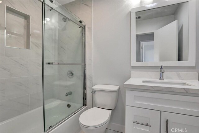 bathroom featuring vanity, bath / shower combo with glass door, and toilet
