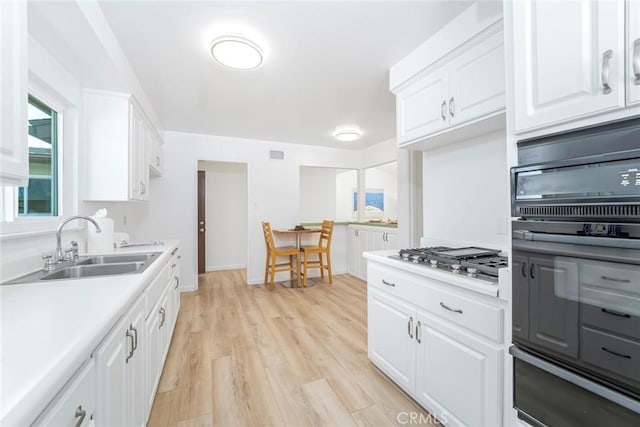 kitchen with oven, a sink, stainless steel gas cooktop, light countertops, and a warming drawer