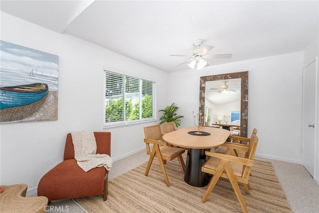 dining area featuring baseboards, ceiling fan, and light carpet