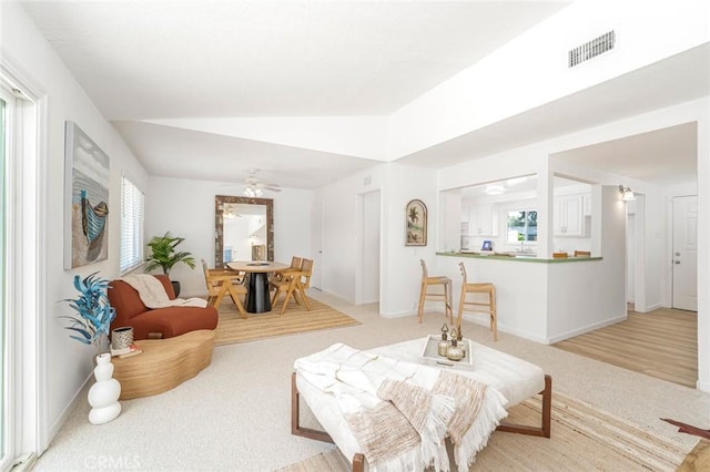living room with light colored carpet, a ceiling fan, baseboards, lofted ceiling, and visible vents