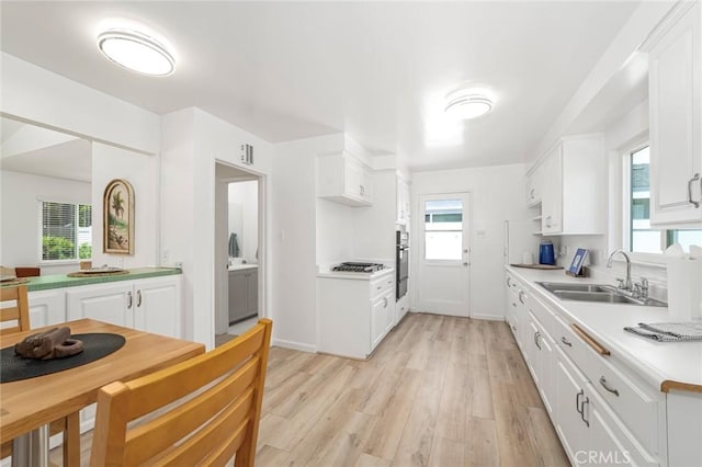 kitchen with white cabinetry, a sink, and light wood-style flooring