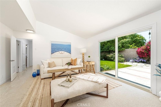 living room featuring light colored carpet, baseboards, and vaulted ceiling