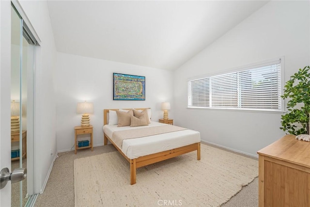 bedroom featuring baseboards, light carpet, a closet, and lofted ceiling