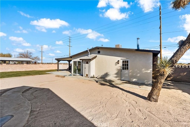 rear view of property featuring a patio, a fenced backyard, and stucco siding
