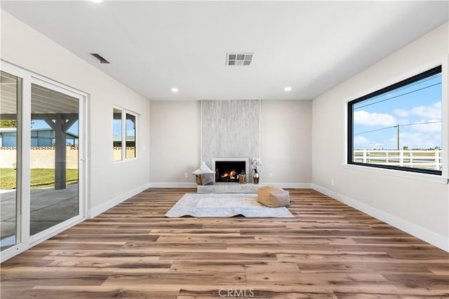 unfurnished living room featuring recessed lighting, visible vents, a wealth of natural light, and wood finished floors
