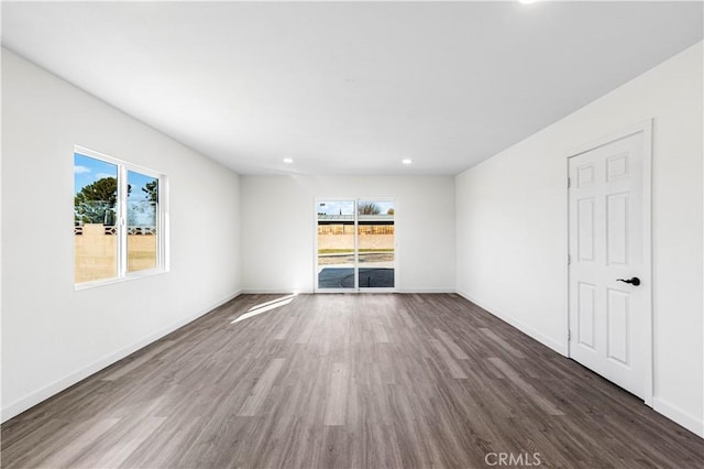 unfurnished living room featuring plenty of natural light, recessed lighting, dark wood-style flooring, and baseboards