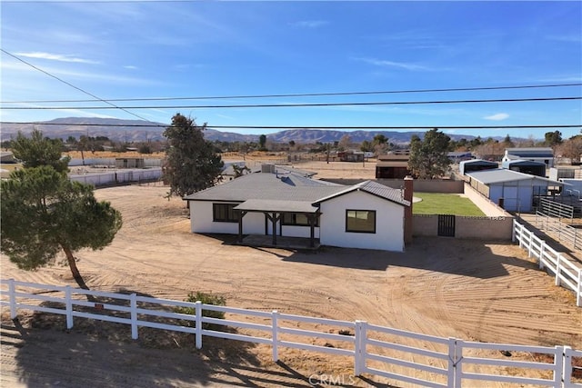 view of front of home with a rural view, fence, a mountain view, and stucco siding