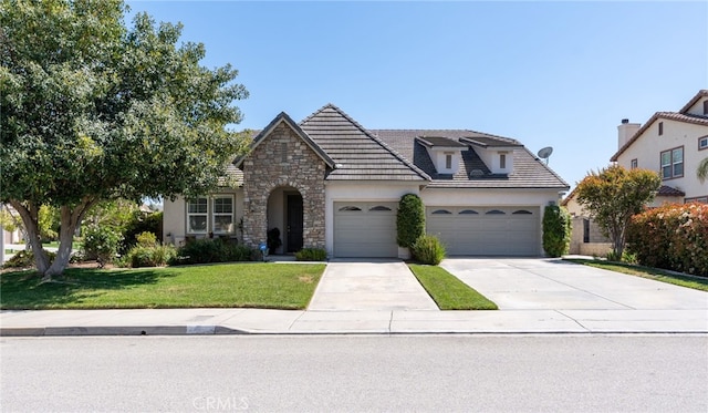 view of front of property featuring driveway, a front lawn, an attached garage, stone siding, and stucco siding