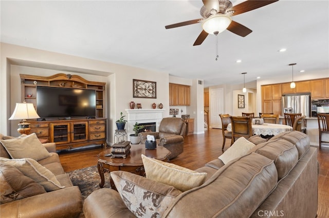 living room featuring a warm lit fireplace, recessed lighting, ceiling fan, and dark wood-style floors