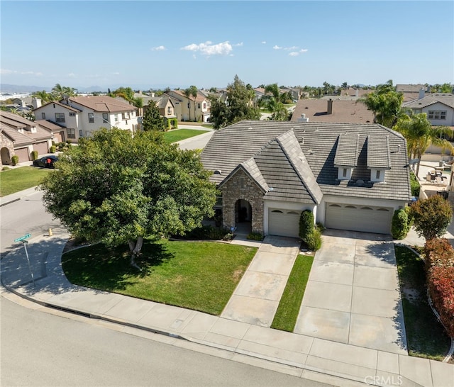 view of front of property featuring driveway, a residential view, stone siding, and a front lawn