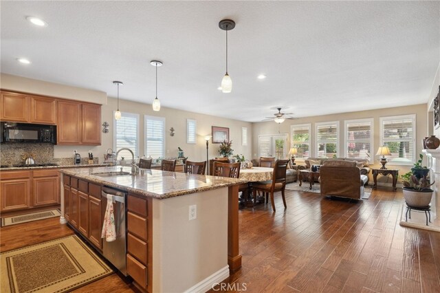 kitchen with stainless steel dishwasher, a ceiling fan, black microwave, open floor plan, and a sink