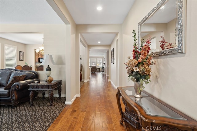 hallway with an inviting chandelier, baseboards, recessed lighting, and wood finished floors