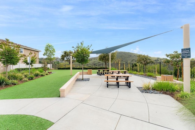 view of property's community with fence, a patio, and a lawn