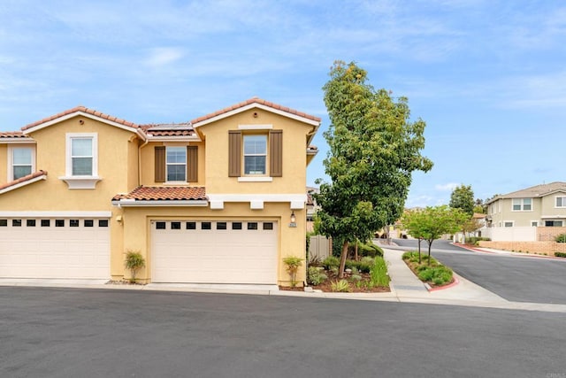view of front of house with a garage, solar panels, a tile roof, and stucco siding