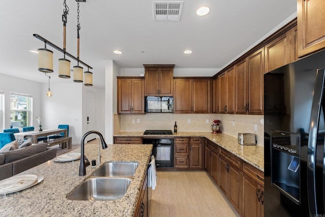 kitchen featuring a sink, open floor plan, tasteful backsplash, visible vents, and black appliances