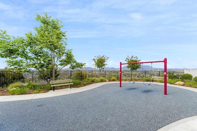community jungle gym with a mountain view and fence