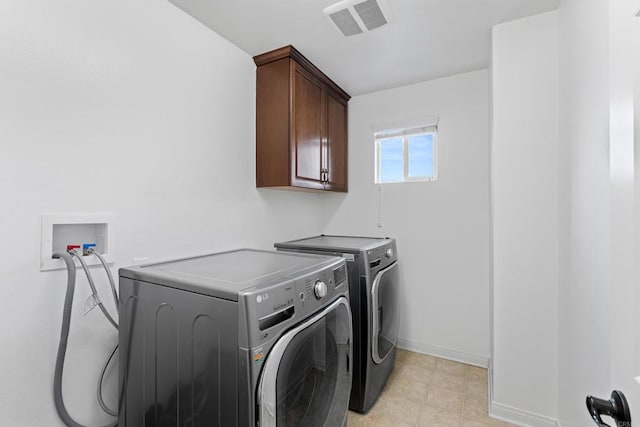 washroom featuring baseboards, visible vents, cabinet space, and washer and dryer