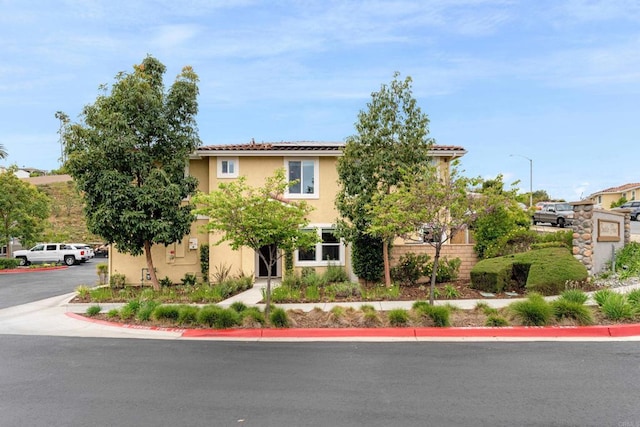 view of front of home featuring roof mounted solar panels and stucco siding
