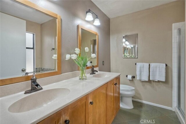 bathroom with a sink, tile patterned floors, toilet, and double vanity
