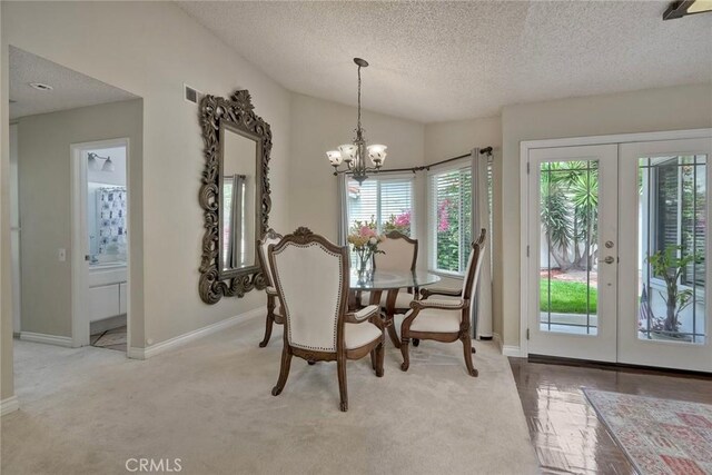 dining room featuring french doors, a textured ceiling, visible vents, a chandelier, and carpet