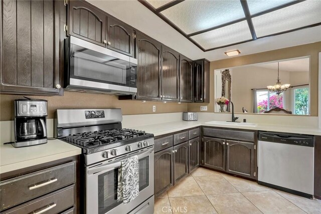 kitchen featuring a sink, appliances with stainless steel finishes, a notable chandelier, and dark brown cabinets