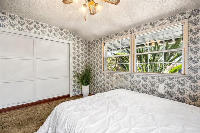 bedroom with a ceiling fan, a textured ceiling, and wallpapered walls