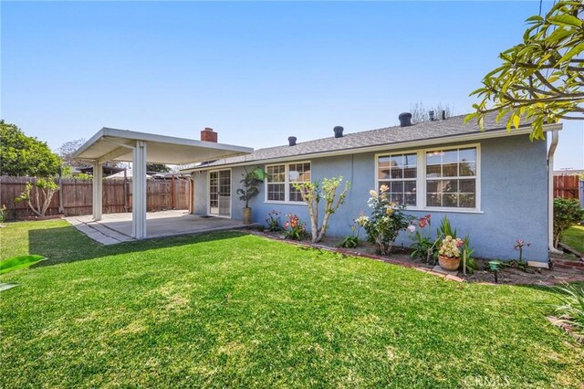 rear view of property with a lawn, fence, a patio area, and stucco siding