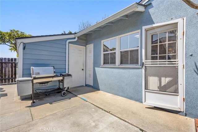 rear view of house with fence, stucco siding, and a patio area