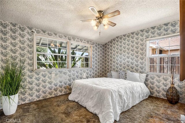 carpeted bedroom featuring a textured ceiling, multiple windows, and wallpapered walls