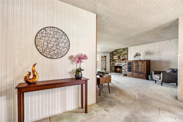 carpeted living room featuring a textured ceiling, a brick fireplace, and vaulted ceiling