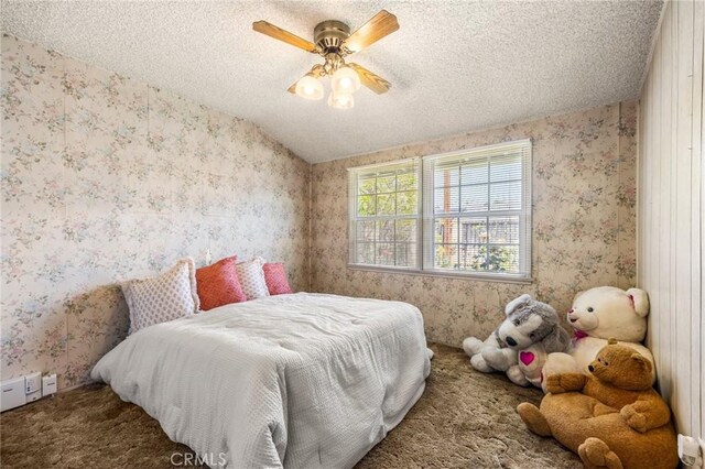 carpeted bedroom featuring a ceiling fan, wallpapered walls, and a textured ceiling