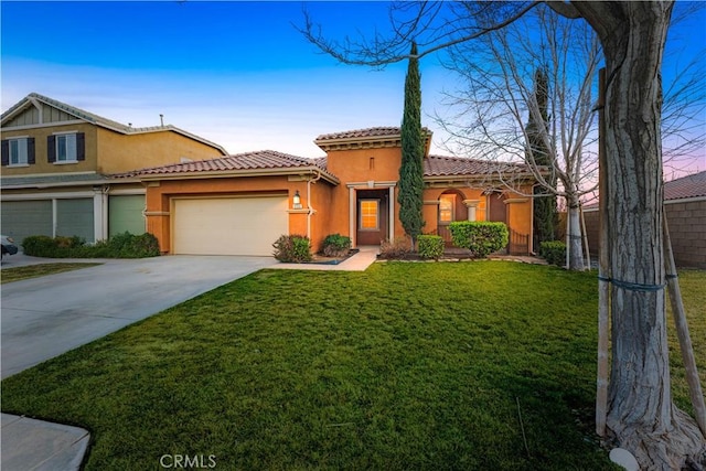 mediterranean / spanish-style home with concrete driveway, an attached garage, a front yard, and stucco siding