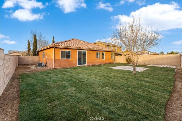 rear view of property with cooling unit, a fenced backyard, stucco siding, a tiled roof, and a yard