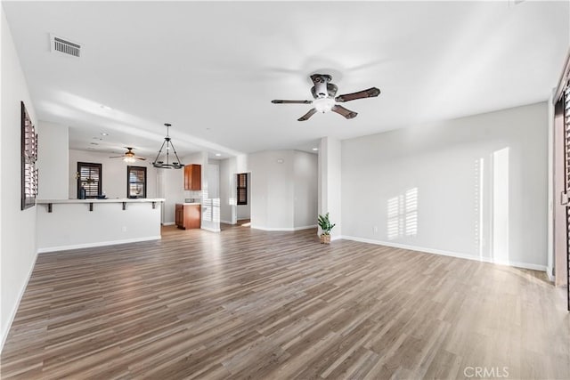 unfurnished living room with visible vents, baseboards, ceiling fan, and wood finished floors