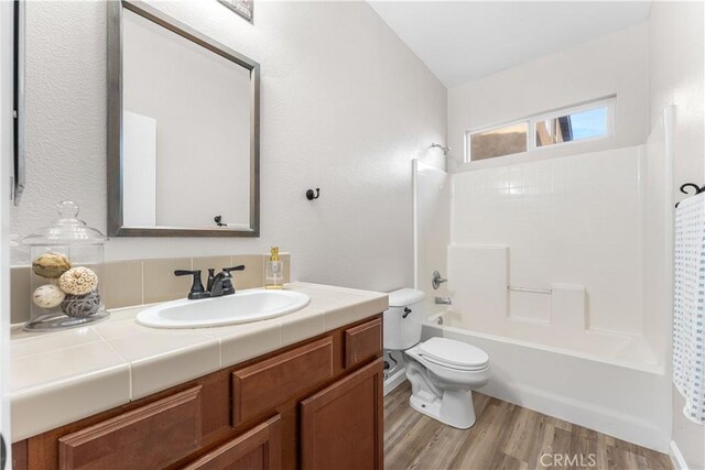 bathroom featuring vanity, shower / bathing tub combination, toilet, and wood finished floors