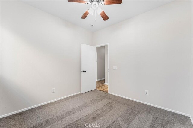 unfurnished room featuring a ceiling fan, baseboards, and carpet