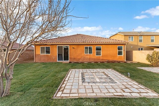 back of house featuring a yard, a patio, a fenced backyard, and stucco siding