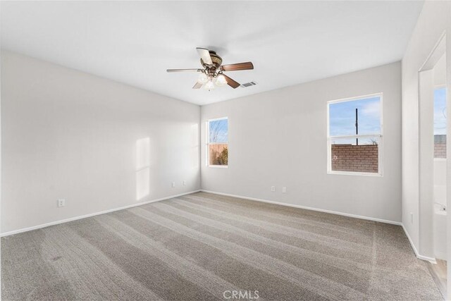 unfurnished room with ceiling fan, visible vents, light carpet, and baseboards