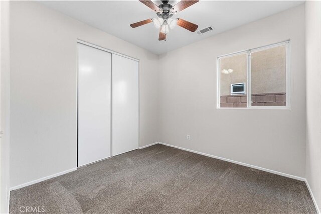 unfurnished bedroom with carpet flooring, ceiling fan, baseboards, visible vents, and a closet