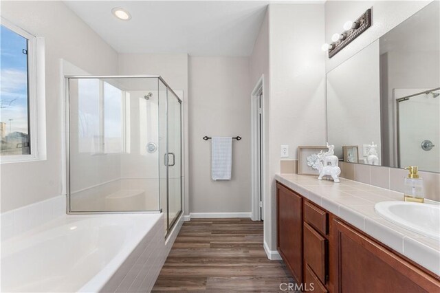 bathroom featuring a bath, vanity, a stall shower, and wood finished floors