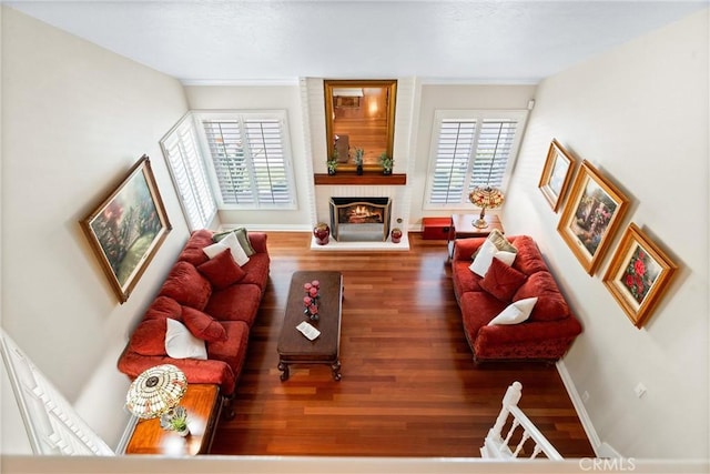 living area with a brick fireplace, baseboards, and wood finished floors