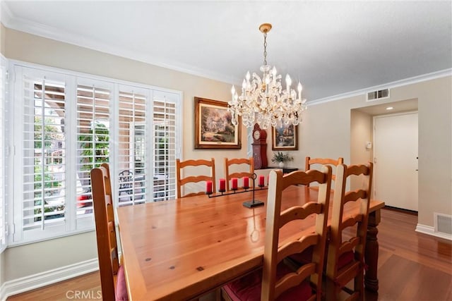 dining area featuring crown molding, a notable chandelier, plenty of natural light, wood finished floors, and visible vents