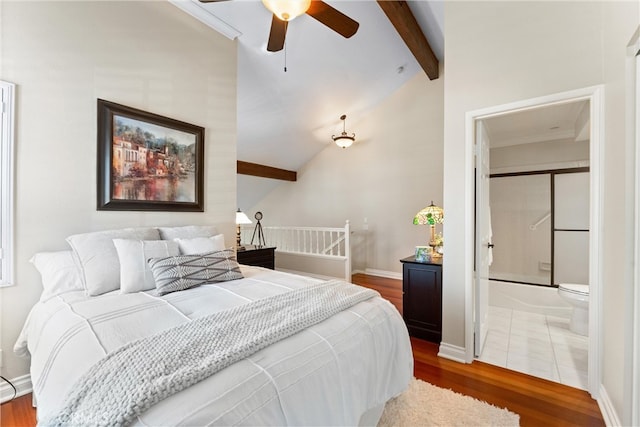 bedroom with baseboards, vaulted ceiling with beams, wood finished floors, and connected bathroom