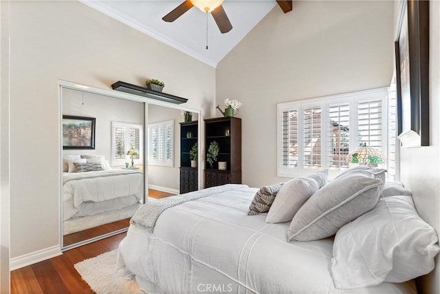 bedroom featuring baseboards, multiple windows, lofted ceiling with beams, and wood finished floors