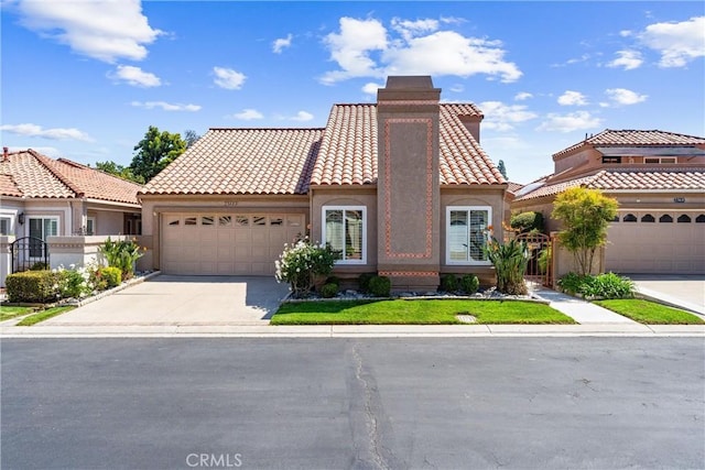 mediterranean / spanish house featuring a tiled roof, a chimney, a garage, concrete driveway, and stucco siding